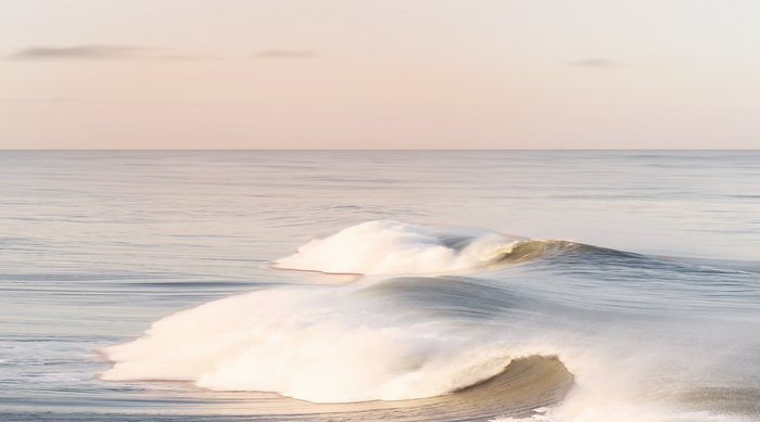 Soft ocean waves rolling under pastel morning light — a calm, natural rhythm reflecting the essence of analog wellness and presence.