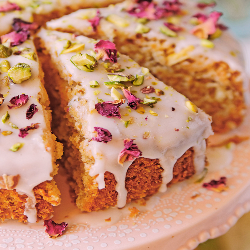 February love cake decorated with rose petals, pistachios, and edible flowers on rustic surface