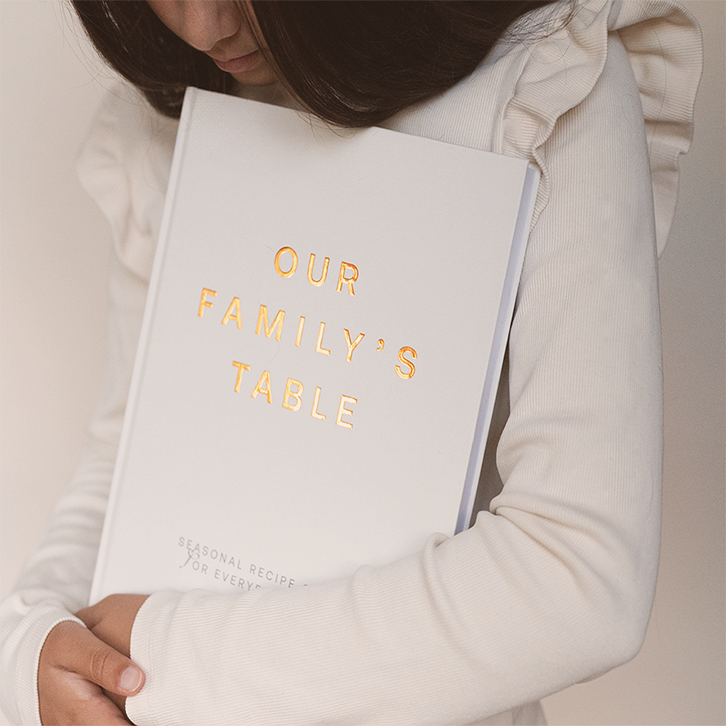 Our Family’s Table cookbook held in hands – tangible family recipe journal