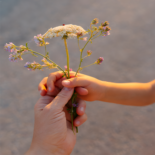 Tender moment of connection—adult and child exchanging wildflowers, symbolizing meaningful and presence
